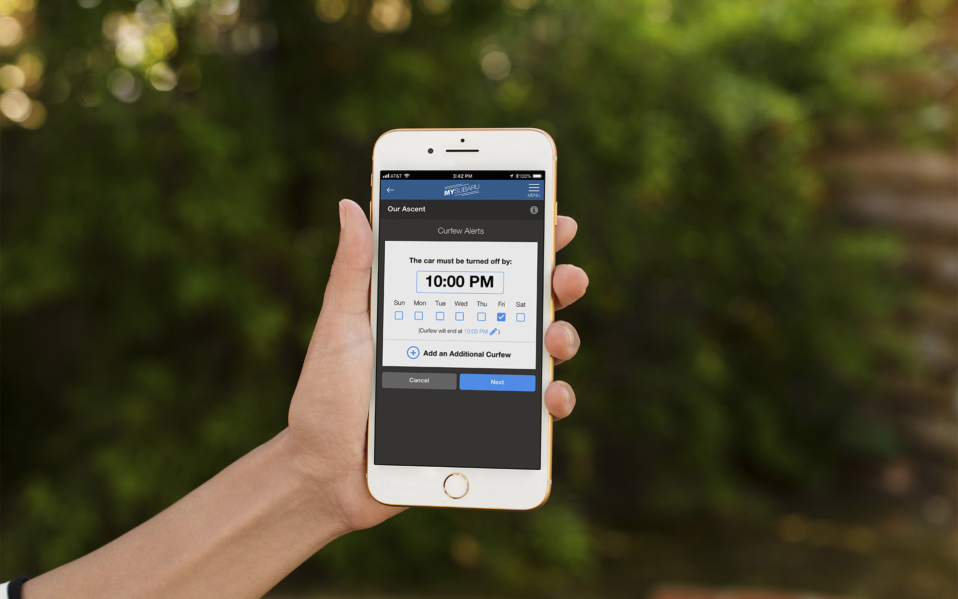 Hand holding an iPhone with the Curfew Alerts page pulled up on the MySubaru app.
