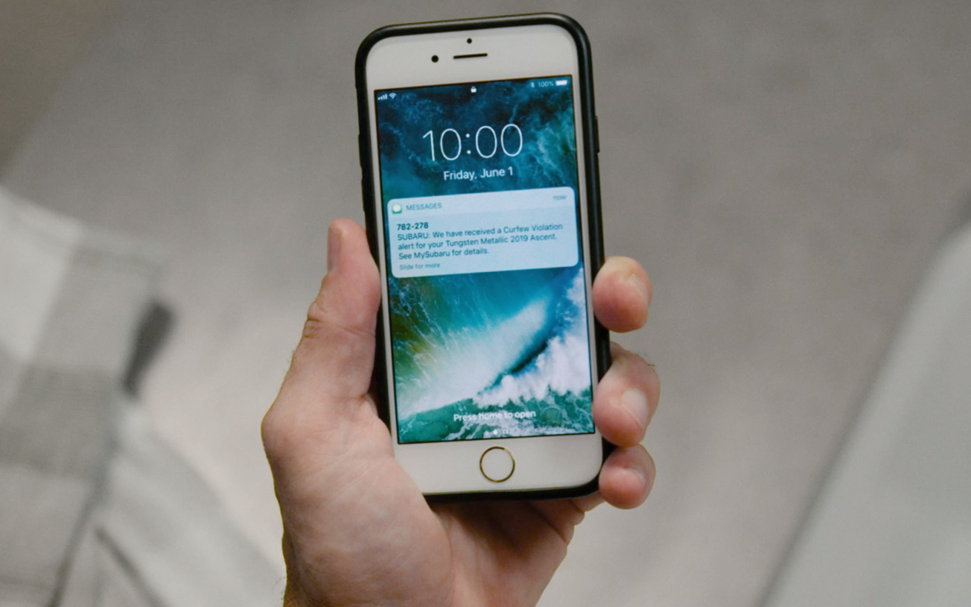 Hand holding an iPhone that is displaying a STARLINK Curfew Violation alert text message.